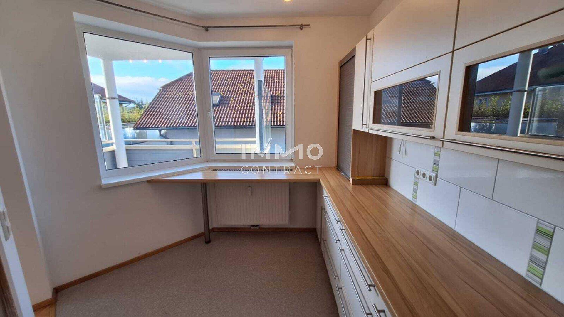 Helle Küche mit Erkerfenster, Holzarbeitsplatte und Platz für einen kleinen Essbereich.