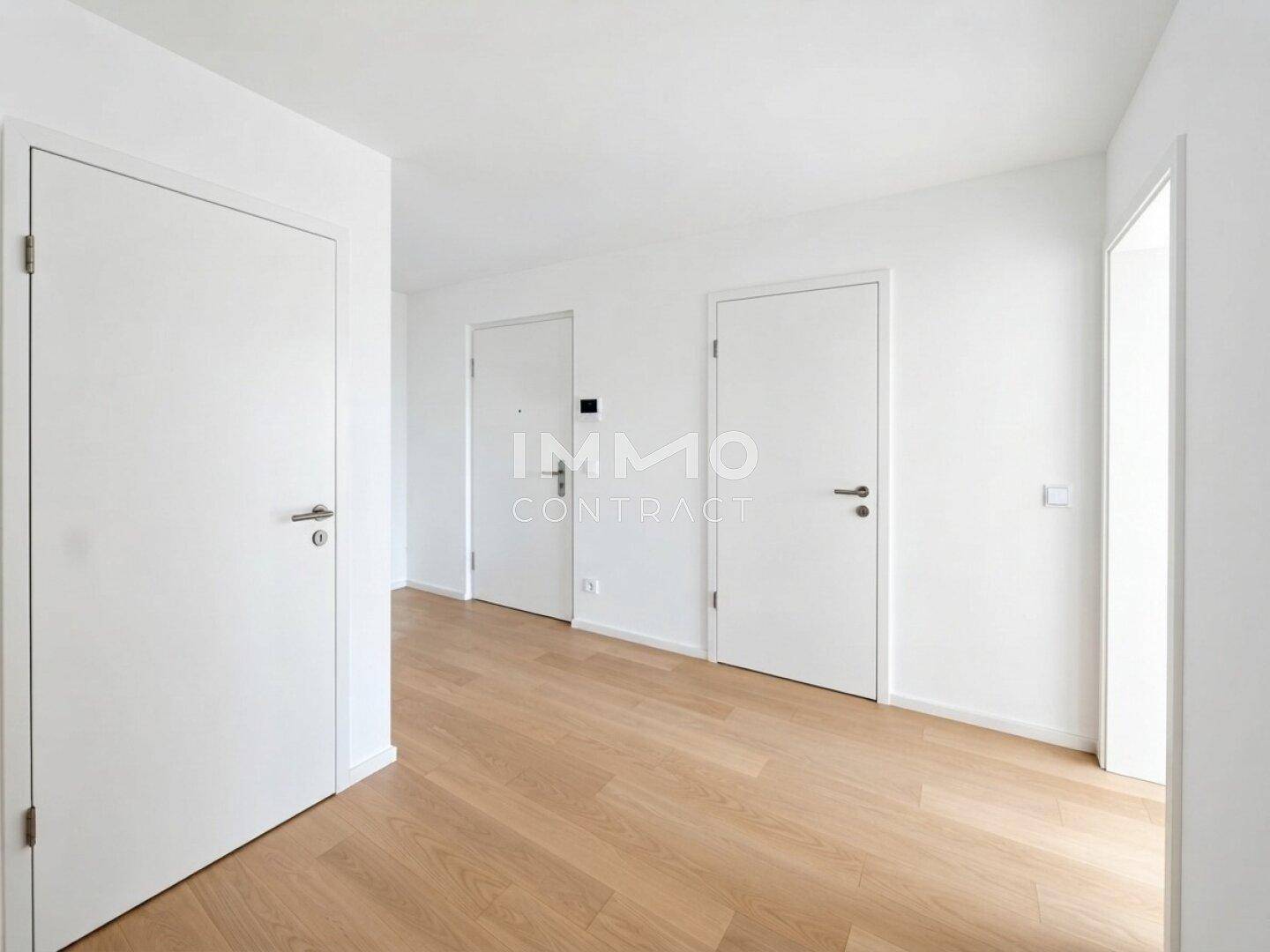 Heller Flur mit modernem Holzfußboden und mehreren weißen Türen, der einen einladenden Eingangsbereich schafft.