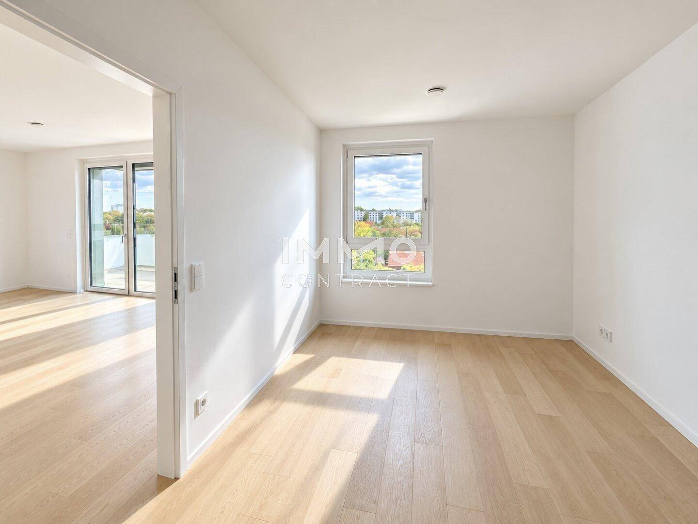 Heller Raum mit Holzboden und Zugang zu einem weiteren Bereich mit Balkon.