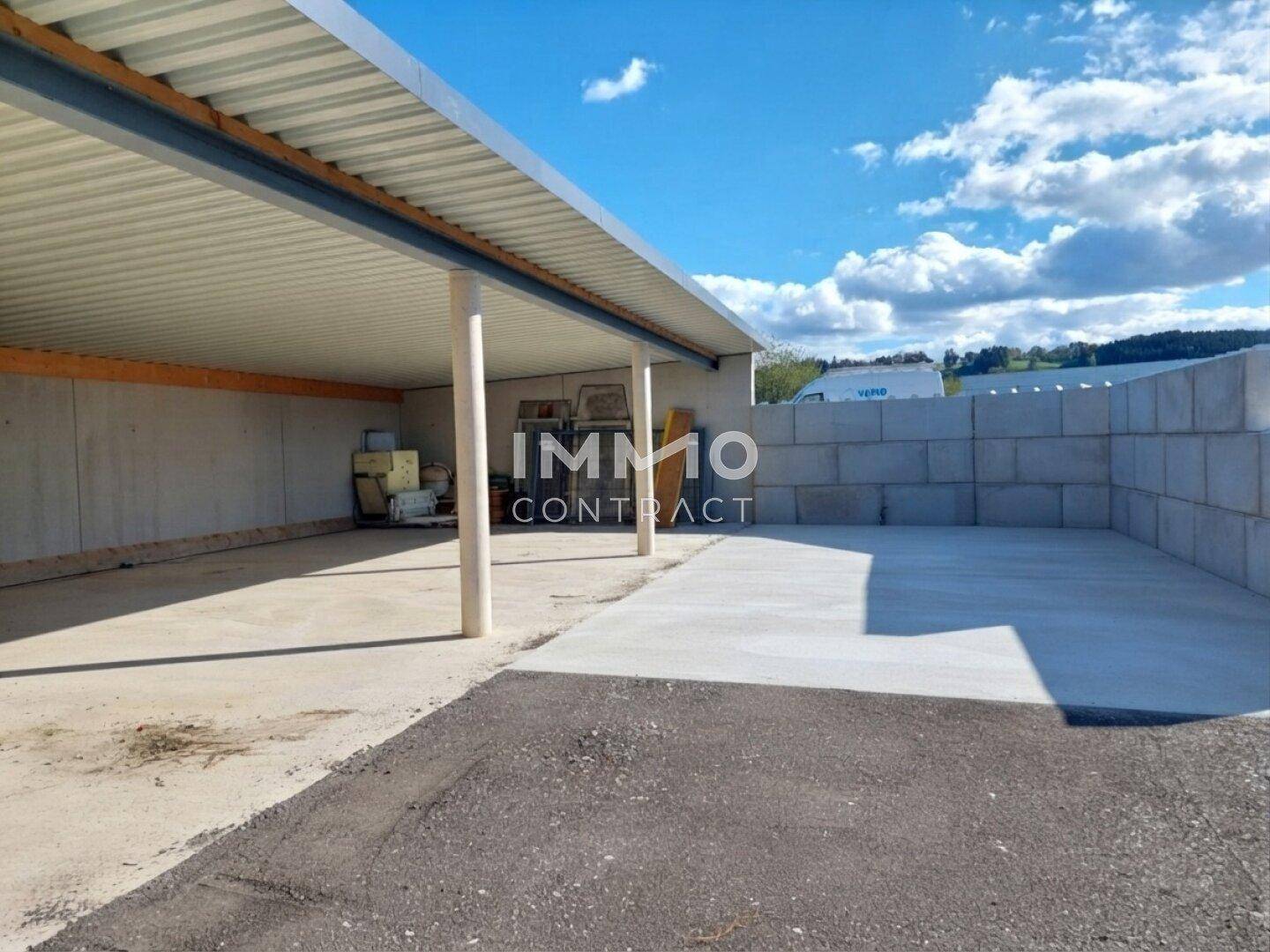 Weitläufiger überdachter Bereich mit Betonboden und angrenzender Betonmauer unter sonnigem Himmel.