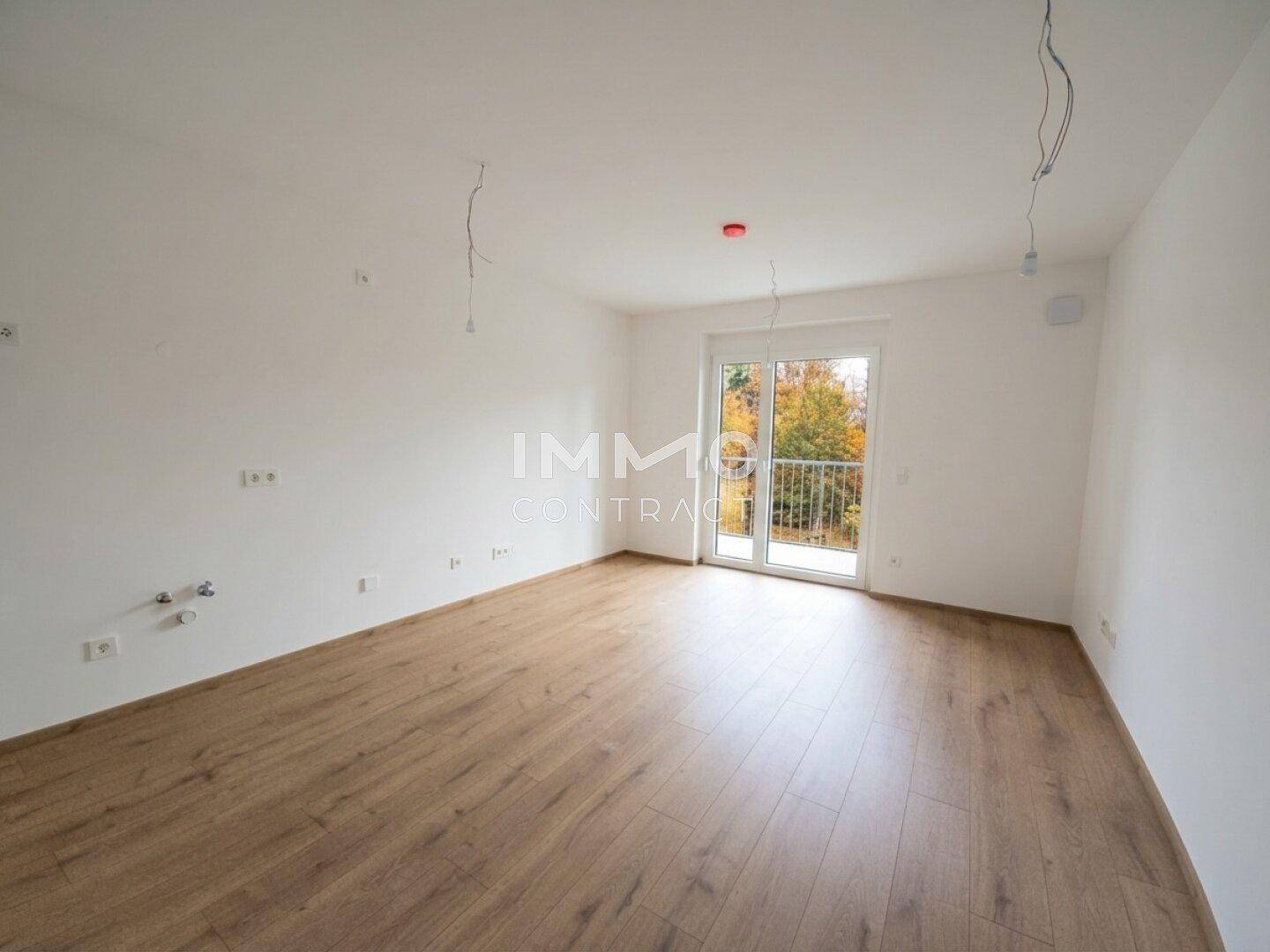 Helles, unmöbliertes Zimmer mit Laminatboden und Zugang zu einem Balkon, bereit zum Einzug.