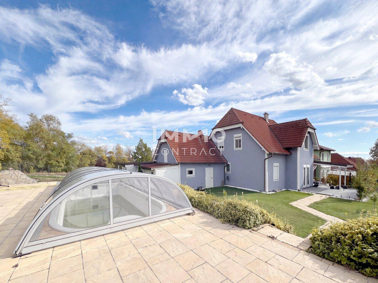 Großzügiger Außenbereich mit überdachtem Pool und Blick auf das moderne Einfamilienhaus.