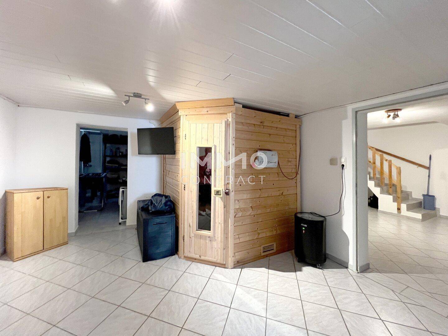 Geräumiger Kellerraum mit integrierter Sauna und Fliesenboden.