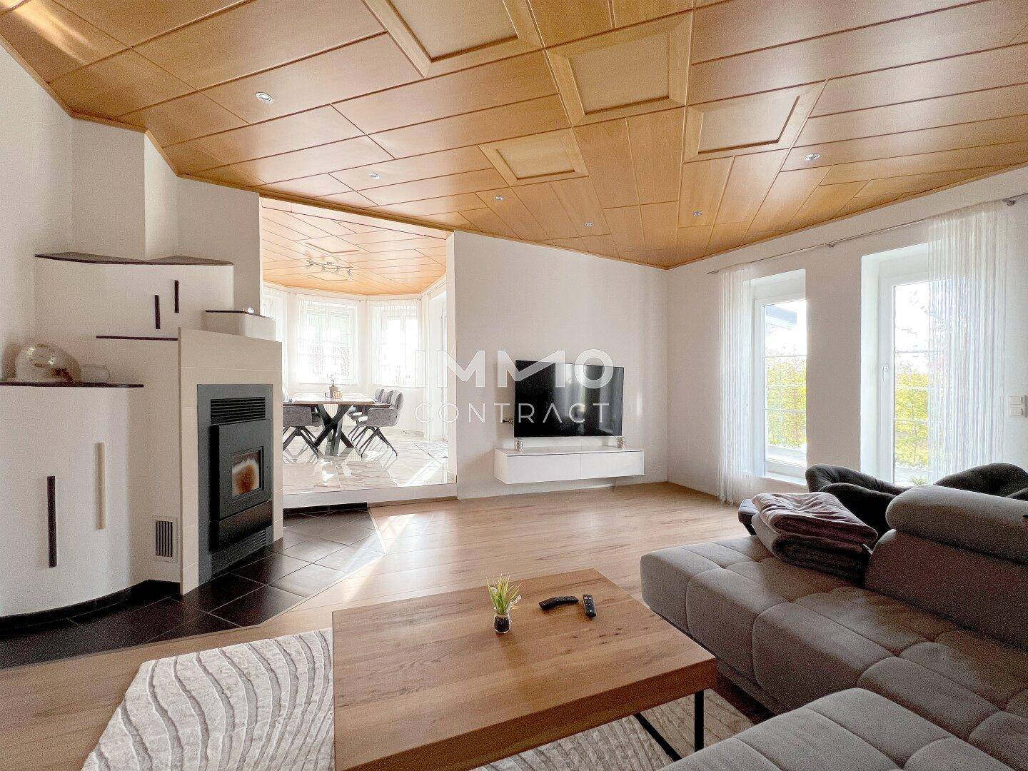 Gemütliches Wohnzimmer mit Holzkassettendecke, Kaminofen und Blick in den Essbereich.