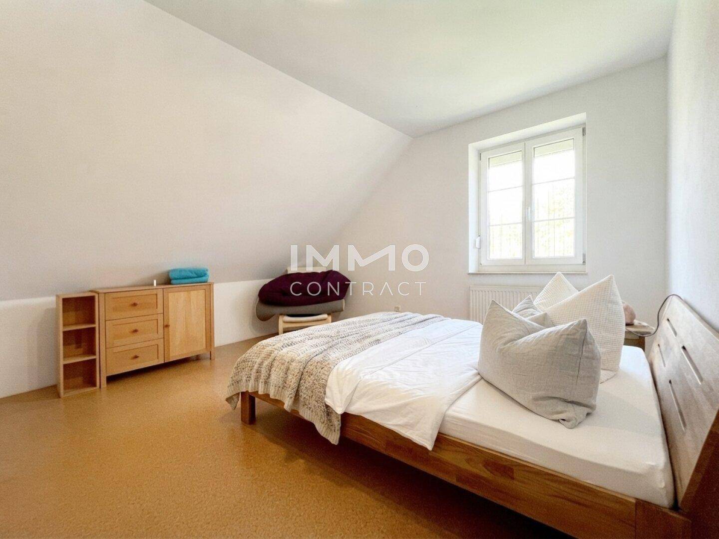 Gemütliches Schlafzimmer im Dachgeschoss mit Holzbett und schrägen Wänden.