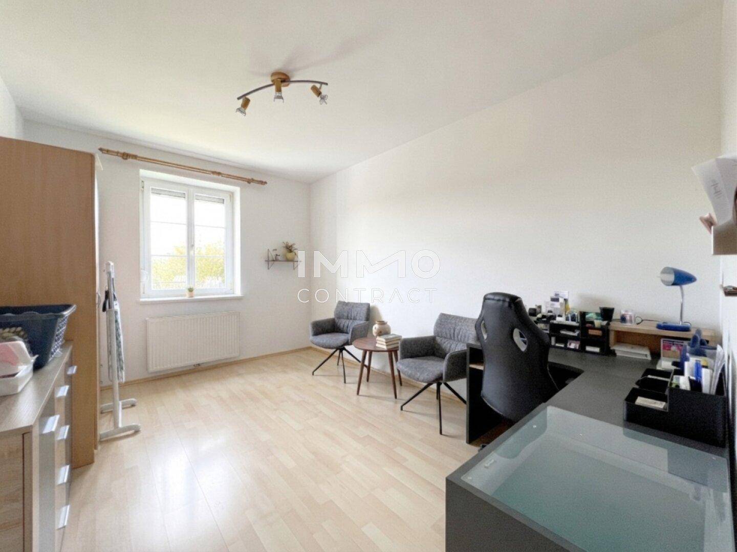 Helles Arbeitszimmer mit Holzfußboden und Blick ins Grüne durch das Fenster.