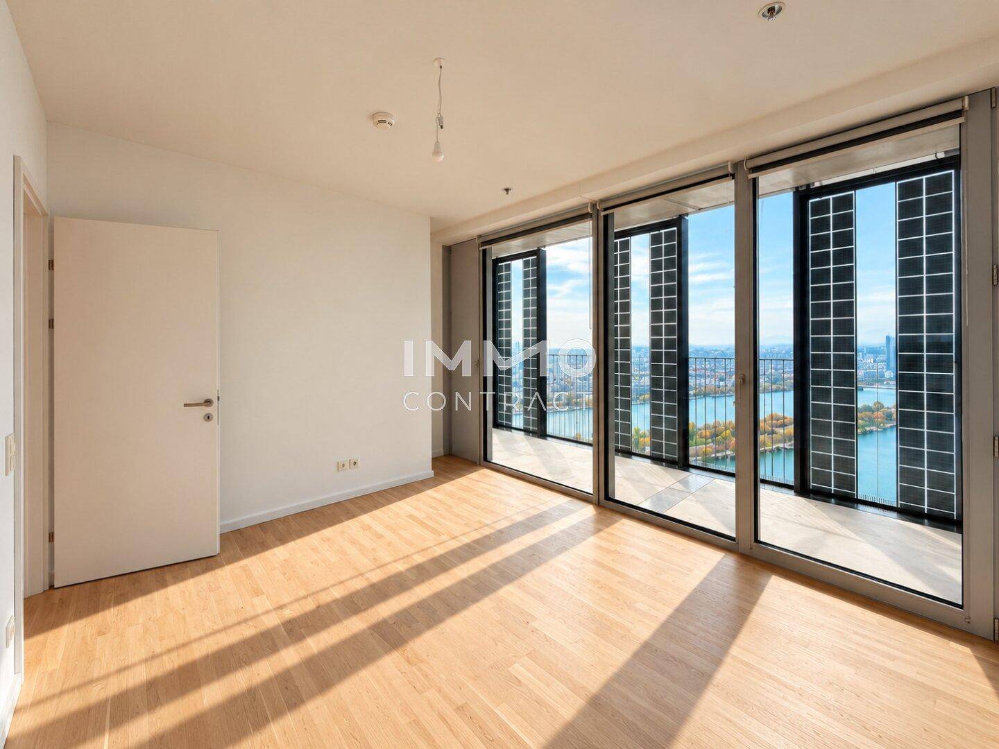 Geräumiges Wohnzimmer mit Holzboden und großen Fenstern, die einen weiten Ausblick bieten.