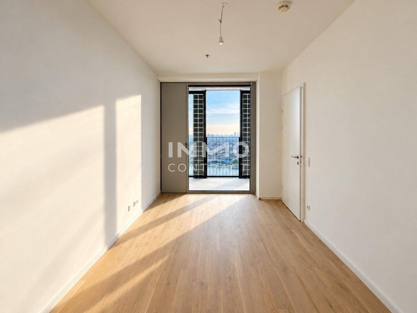Helles Schlafzimmer mit Holzboden und Zugang zu einem Balkon mit Stadtblick.