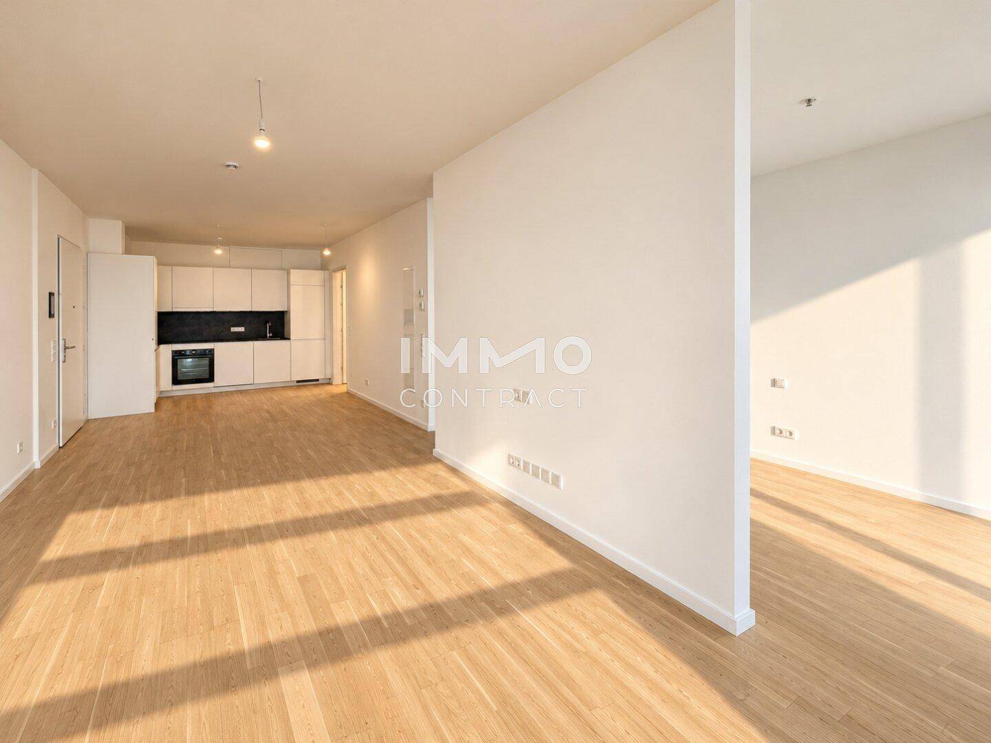 Offener Wohnbereich mit Holzboden und integrierter moderner Küche in minimalistischem Design.