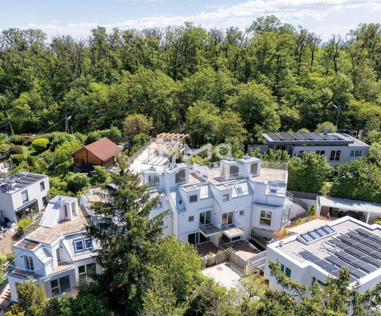 Luftaufnahme einer modernen Wohnanlage mit Dachterrassen und umgebender Natur.