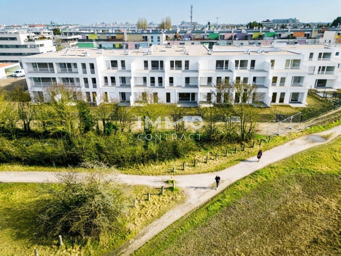 Weitläufige Wohnanlage mit moderner Architektur, angrenzend an Grünflächen und Spazierwege.