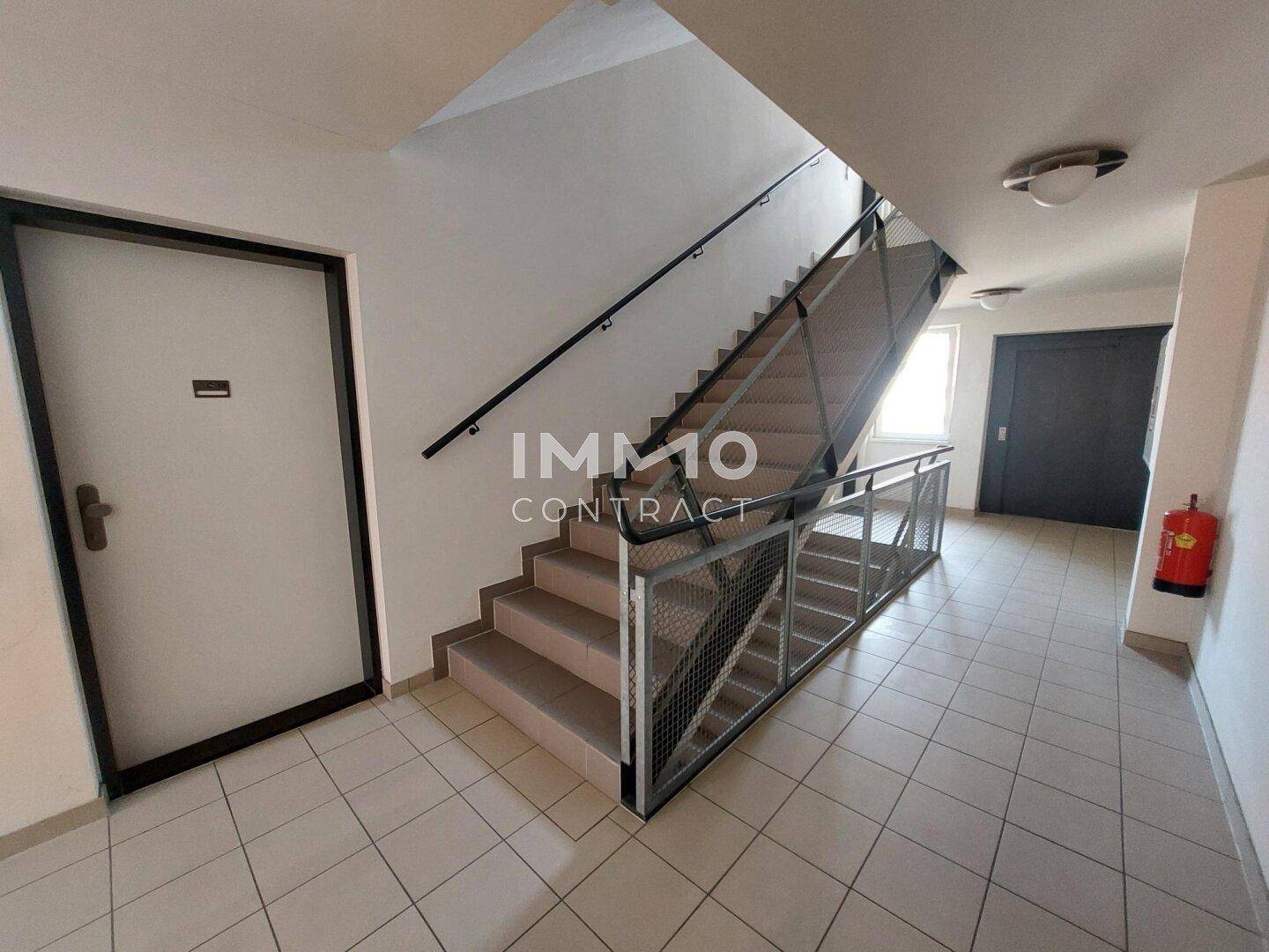 Treppenhaus in einem Mehrfamilienhaus mit Fliesenboden und Metallgeländer.
