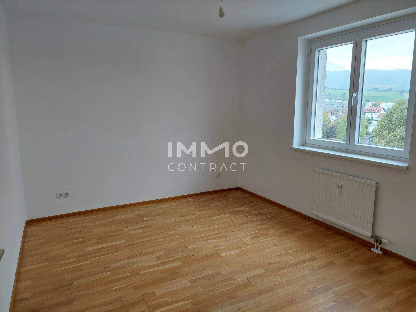 Geräumiges Zimmer mit Parkettboden, Fenster und Blick auf die Landschaft.