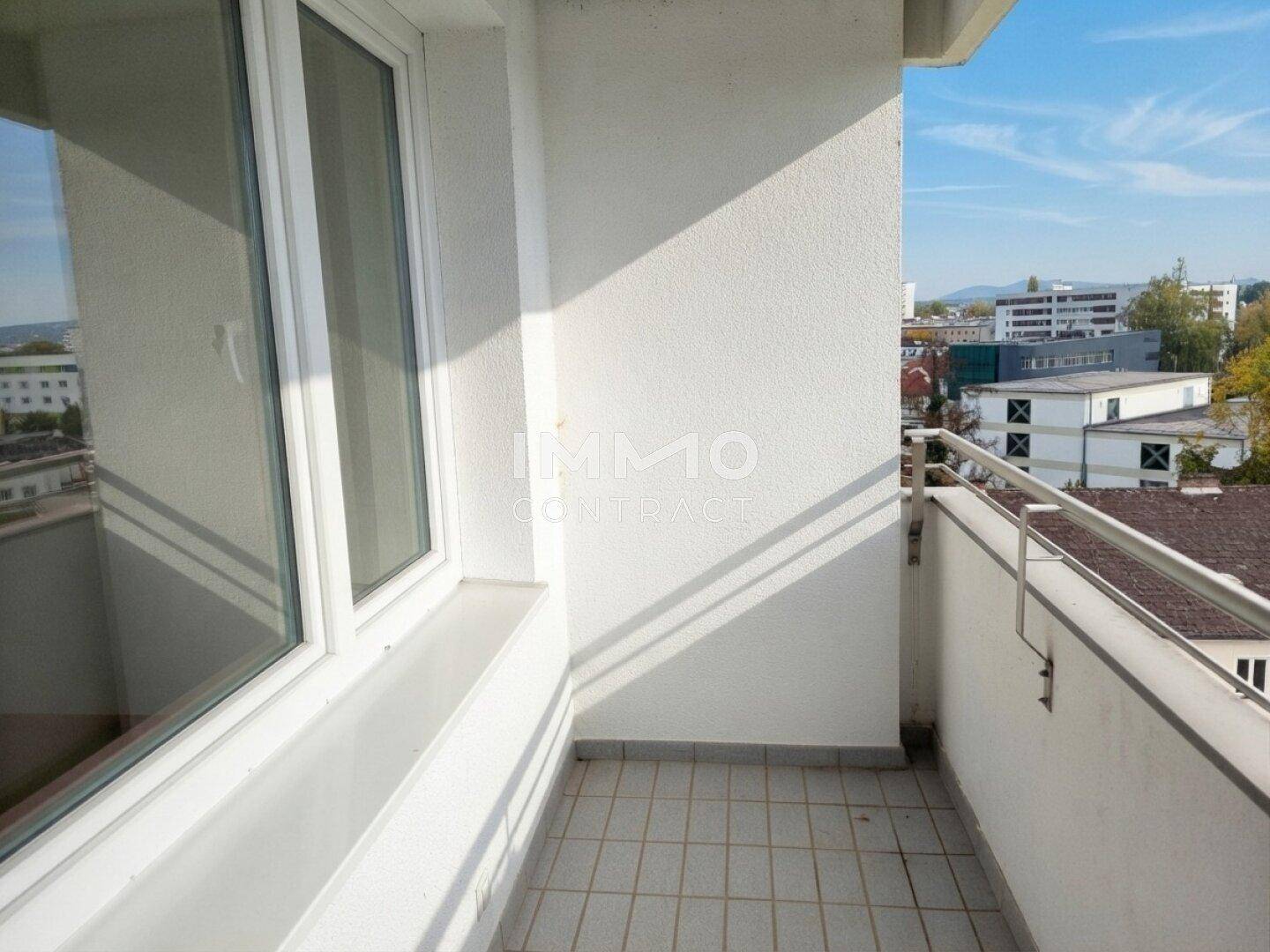 Schmaler Balkon mit Fliesenboden und Blick auf die Stadt.