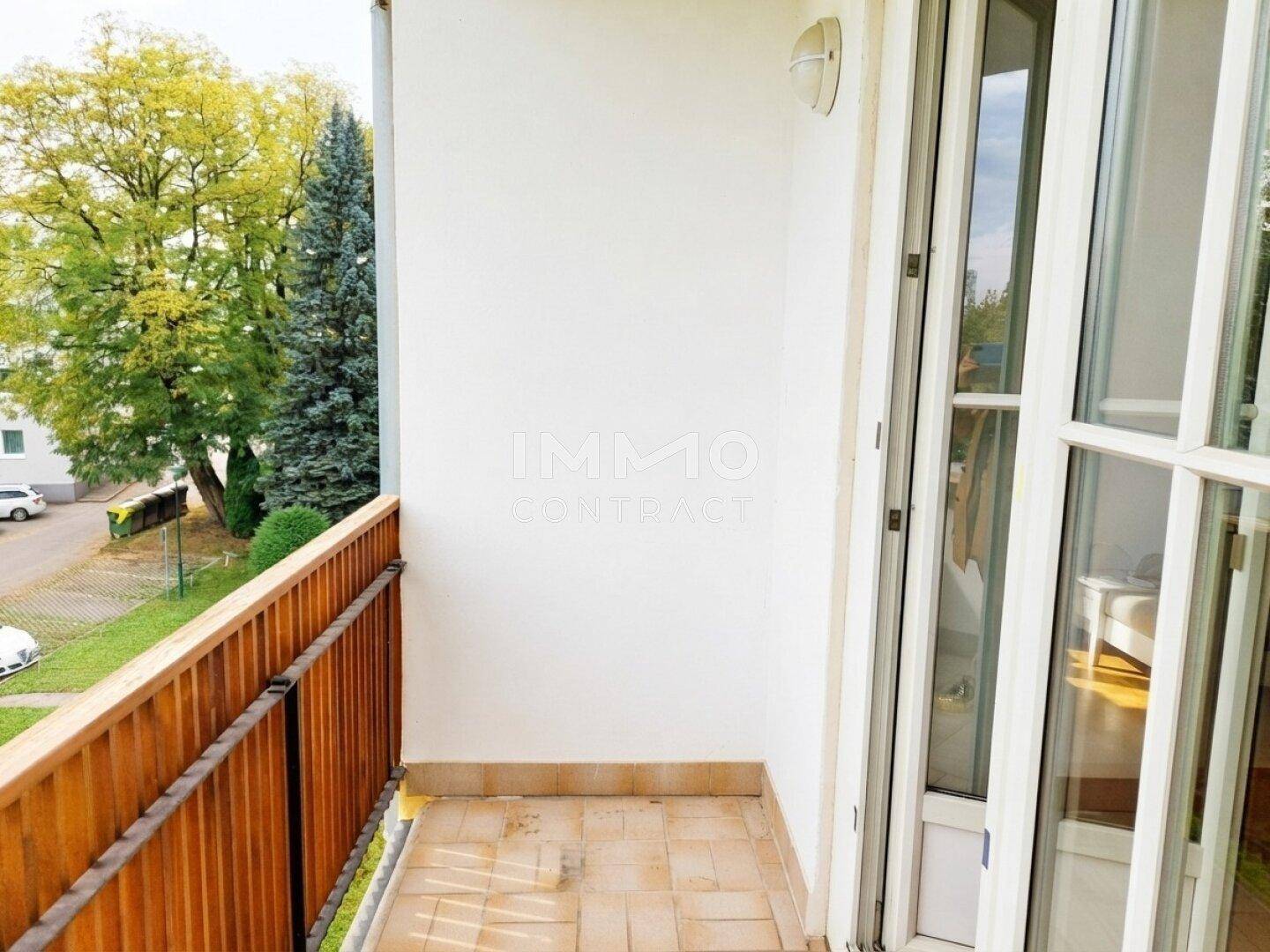 Kleiner Balkon mit Holzbalkon und Blick ins Grüne, ideal für entspannte Stunden im Freien.