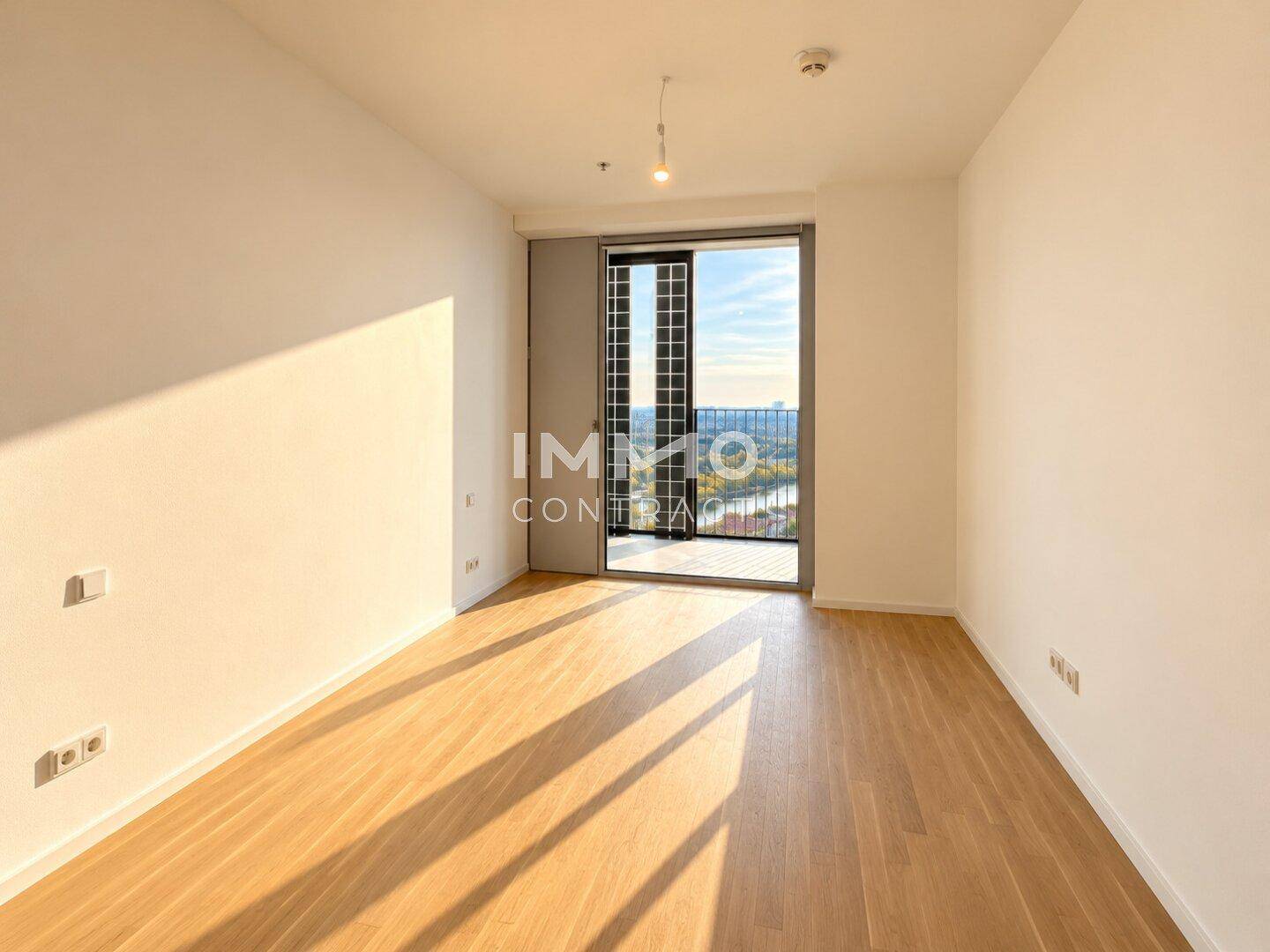 Helles Zimmer mit Parkettboden und Zugang zu einem Balkon mit Stadtblick.