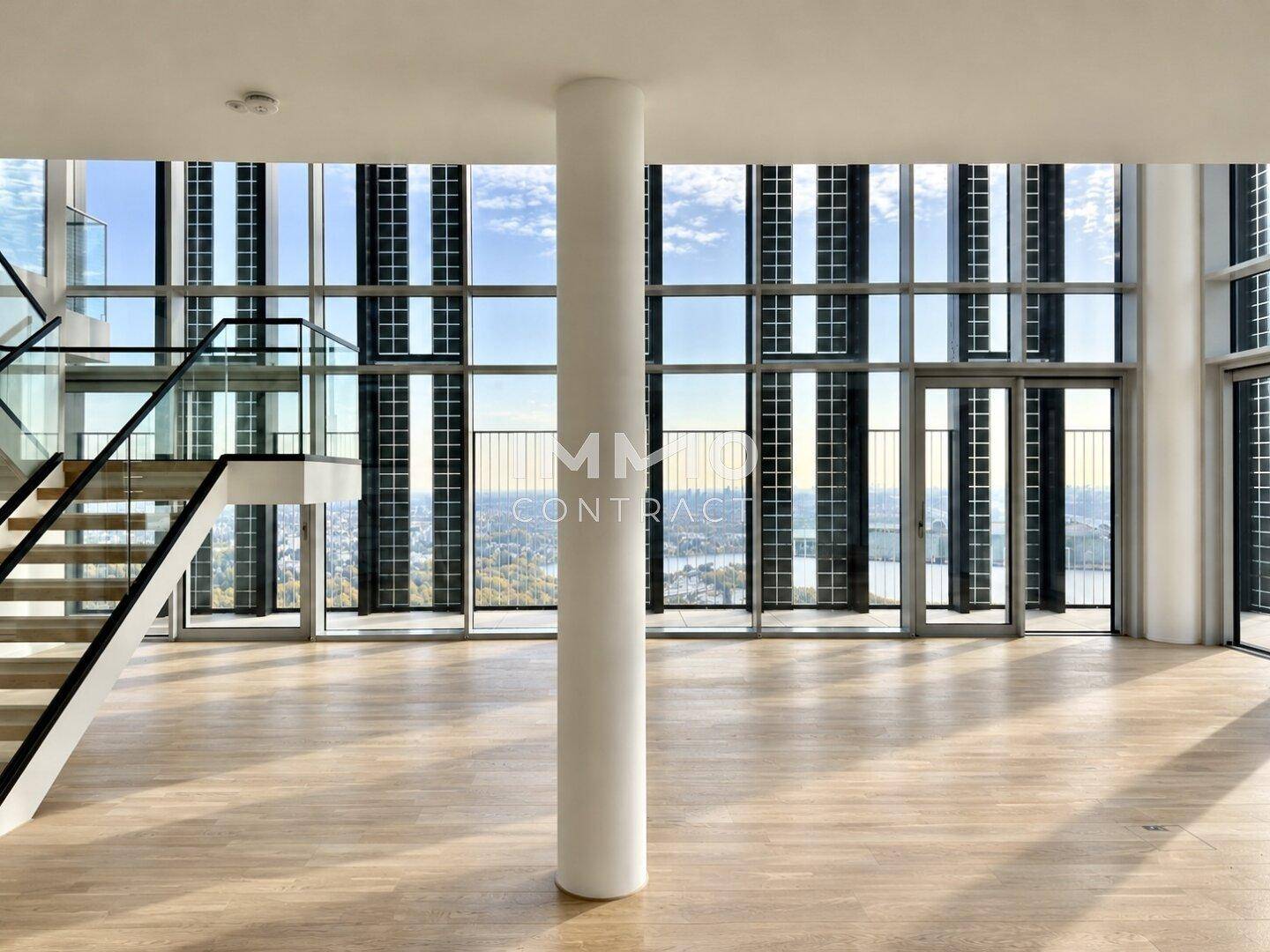 Heller, offener Wohnbereich mit Säule, Parkettboden und raumhohen Fenstern mit Panoramablick.