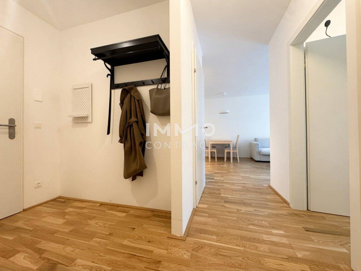 Heller Eingangsbereich mit Garderobe und Parkettboden, der zum offenen Wohnbereich führt.