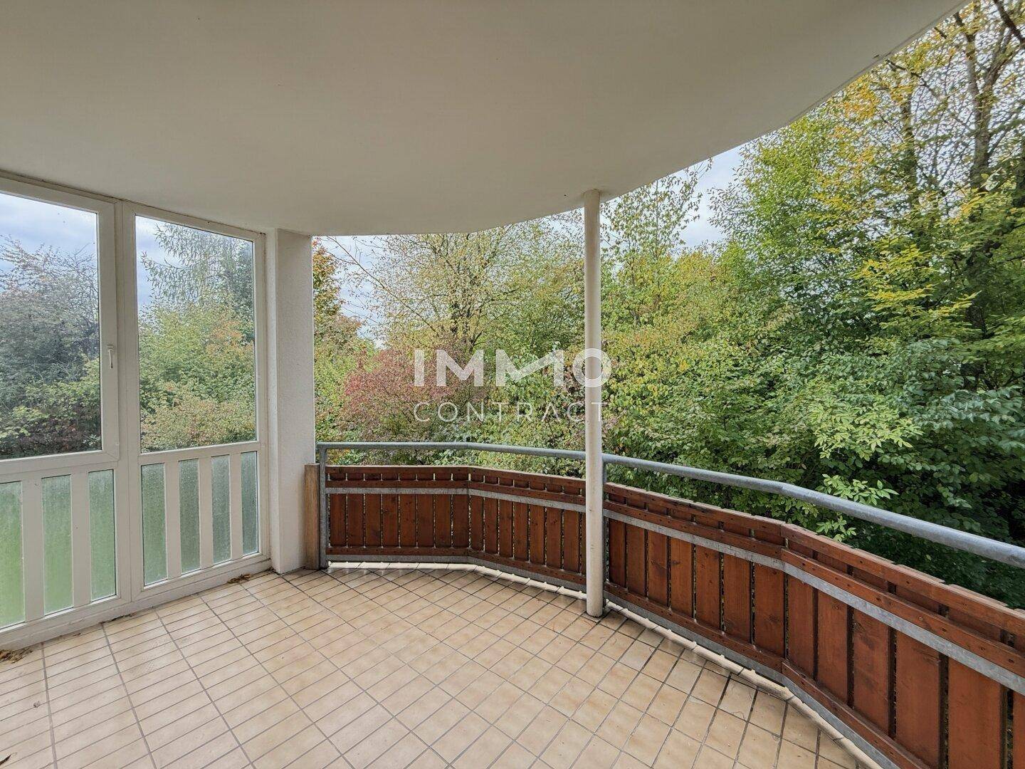 Großer Balkon mit Fliesenboden und Holzelementen, umgeben von Bäumen und Natur.