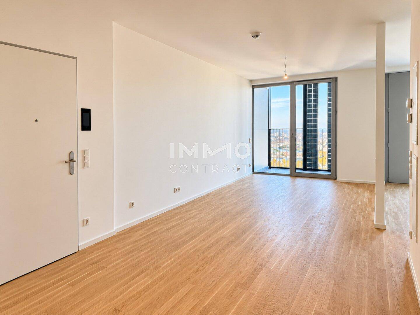 Geräumiger, heller Wohnbereich mit Holzboden und Zugang zu einem Balkon.