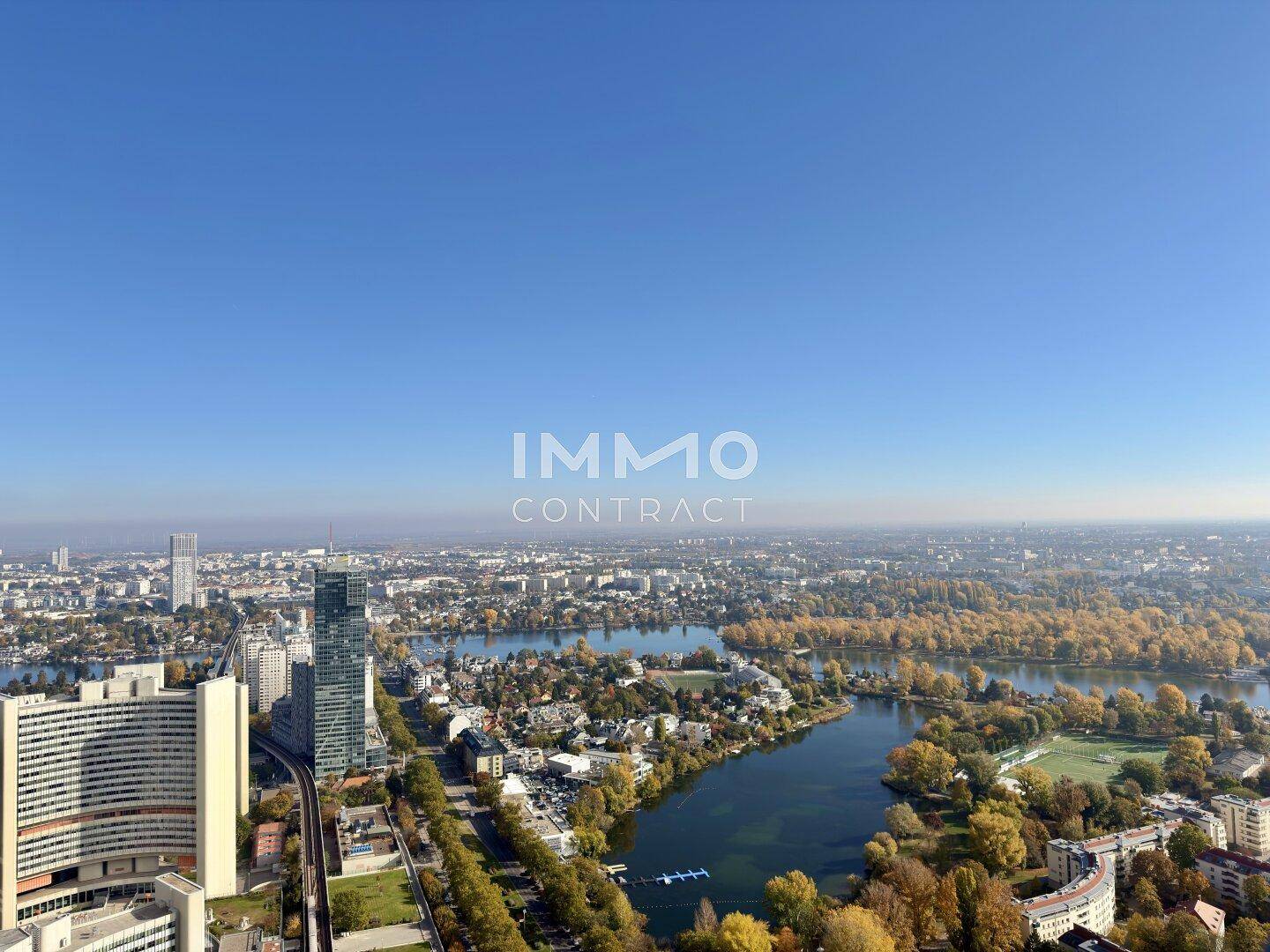 Panoramablick über die Stadt, den See und die umliegende Landschaft an einem sonnigen Tag.