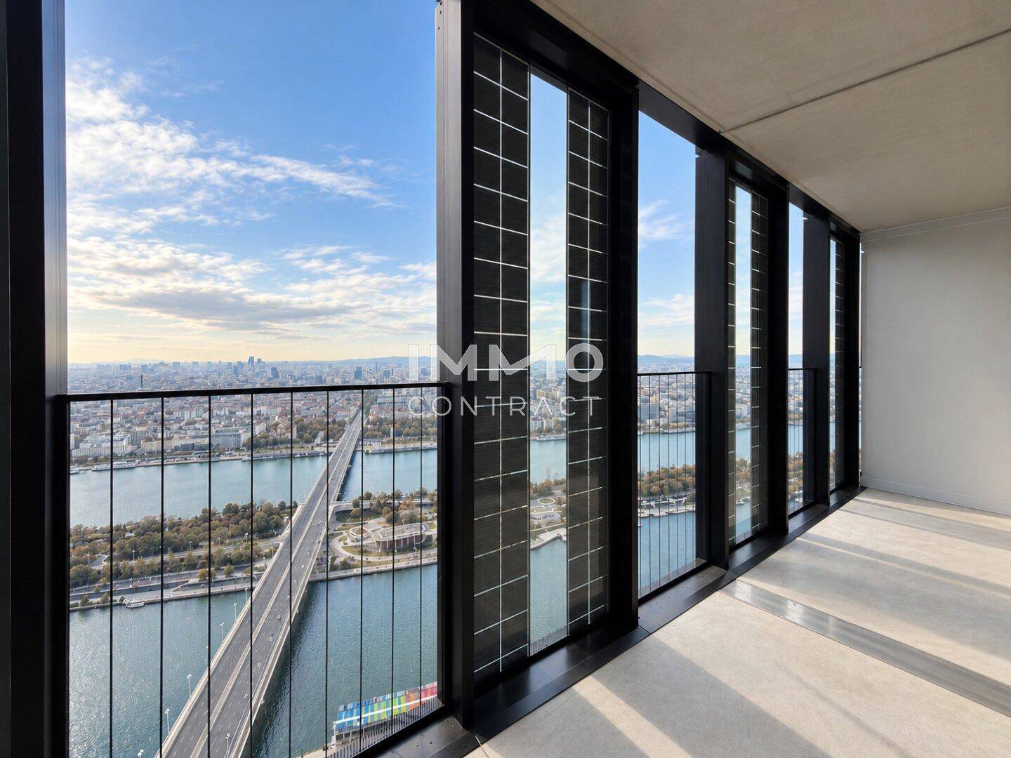 Geräumiger Balkon mit Glasbrüstung und beeindruckendem Panoramablick auf die Stadt und den Fluss.