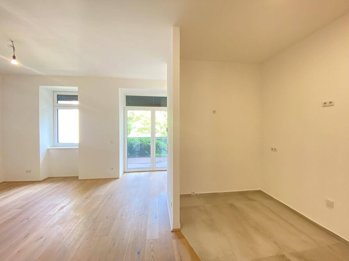 Wohnesszimmer mit Nische für Küche und Zugang zur Terrasse