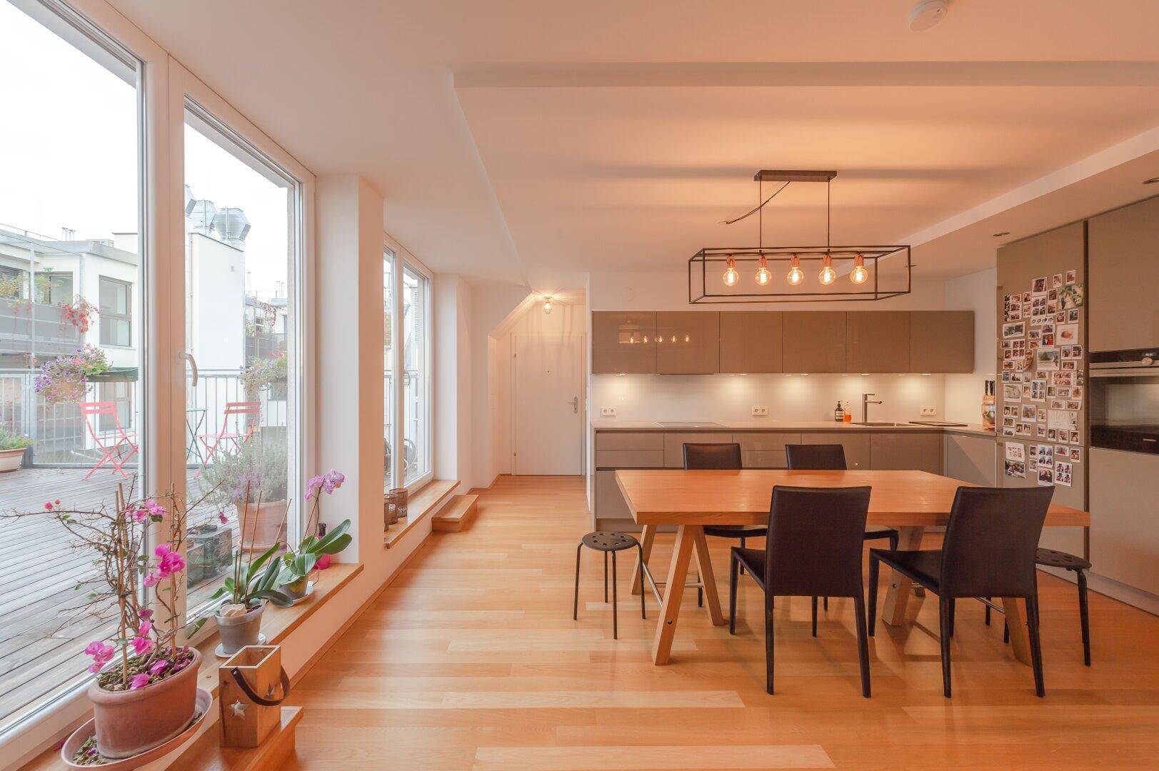 Geräumiger Wohn- und Essbereich mit moderner Küche und großen Fenstern zur Dachterrasse.
