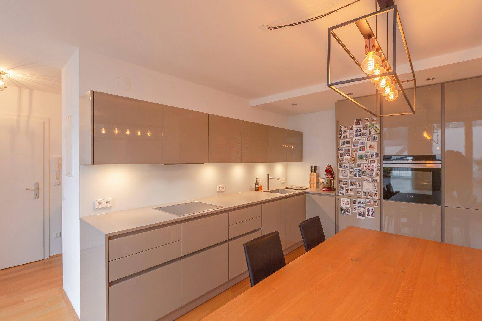 Moderne Einbauküche mit glänzenden Fronten, integrierten Geräten und viel Arbeitsfläche.