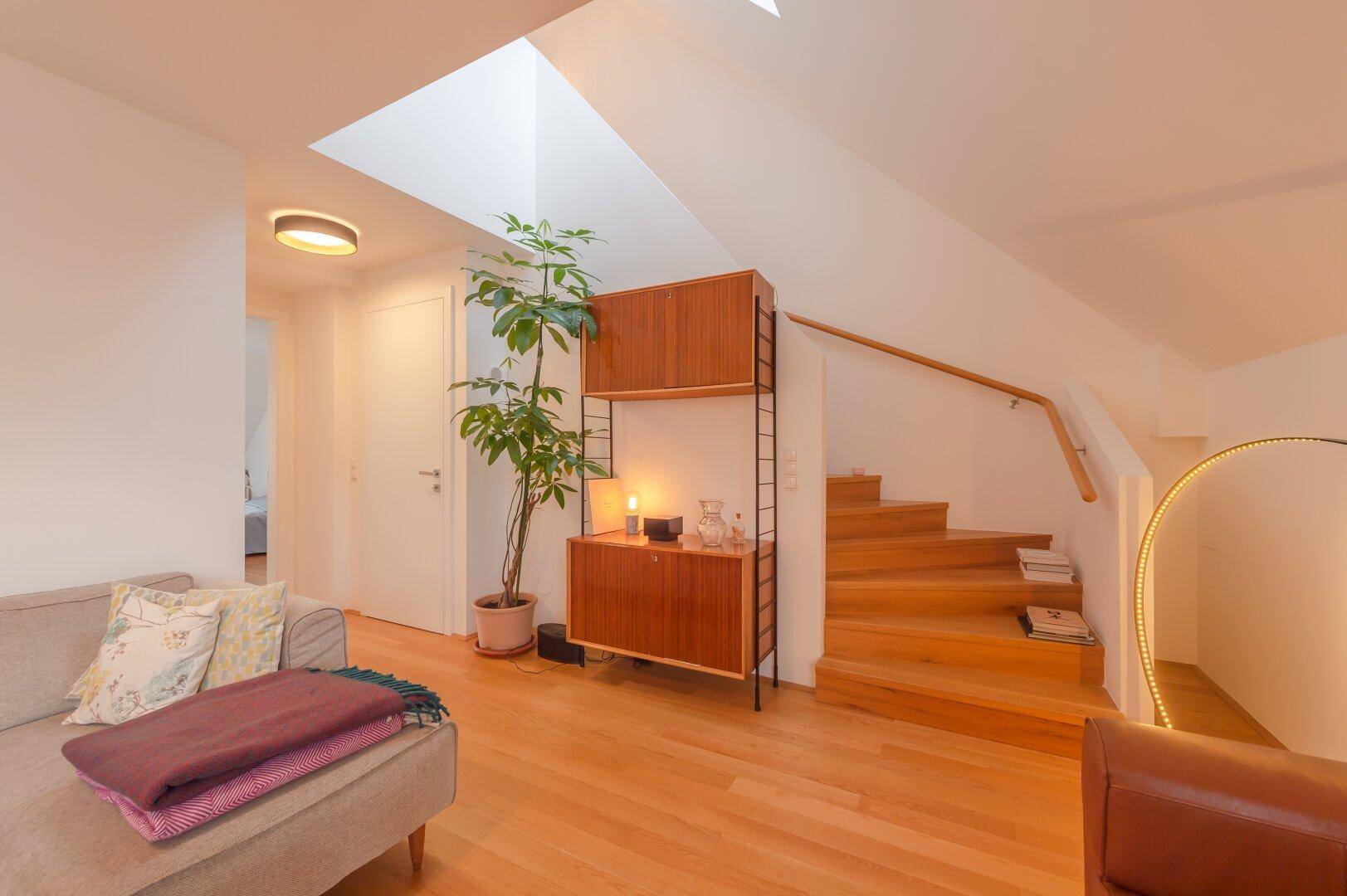 Heller Flur mit Holztreppe, Oberlicht und stilvollem Regal im modernen Design.