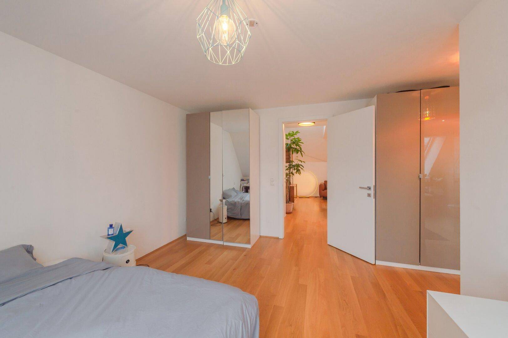 Geräumiges Schlafzimmer mit Holzboden, Einbauschränken und Zugang zum Flur.