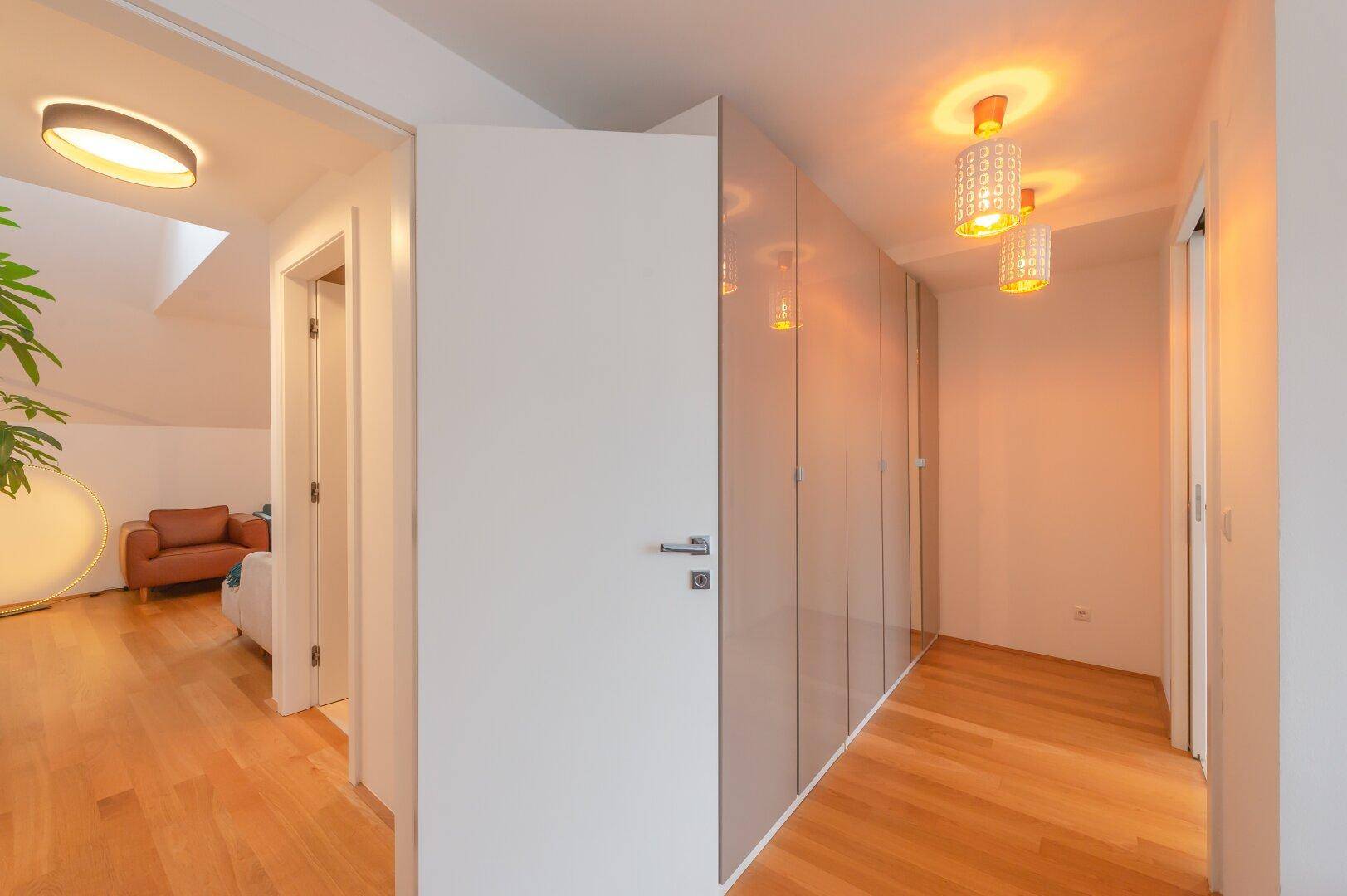 Heller Flur mit Einbauschränken und Zugang zum Wohnbereich im Dachgeschoss.