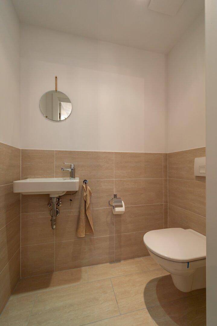 Kleines Gäste-WC mit Waschbecken und Toilette in neutralen, hellen Farben.