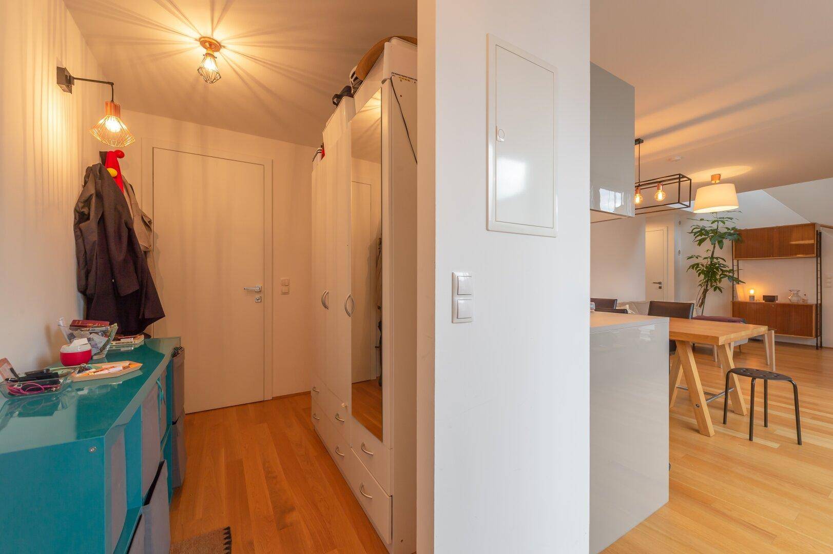 Eingangsbereich mit Garderobe, Spiegel und Zugang zum offenen Wohnbereich.