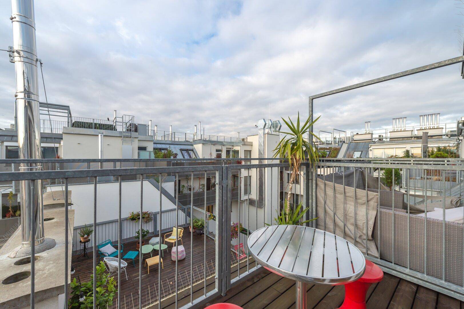 Weitläufige Dachterrasse mit verschiedenen Sitzbereichen und urbanem Ausblick.