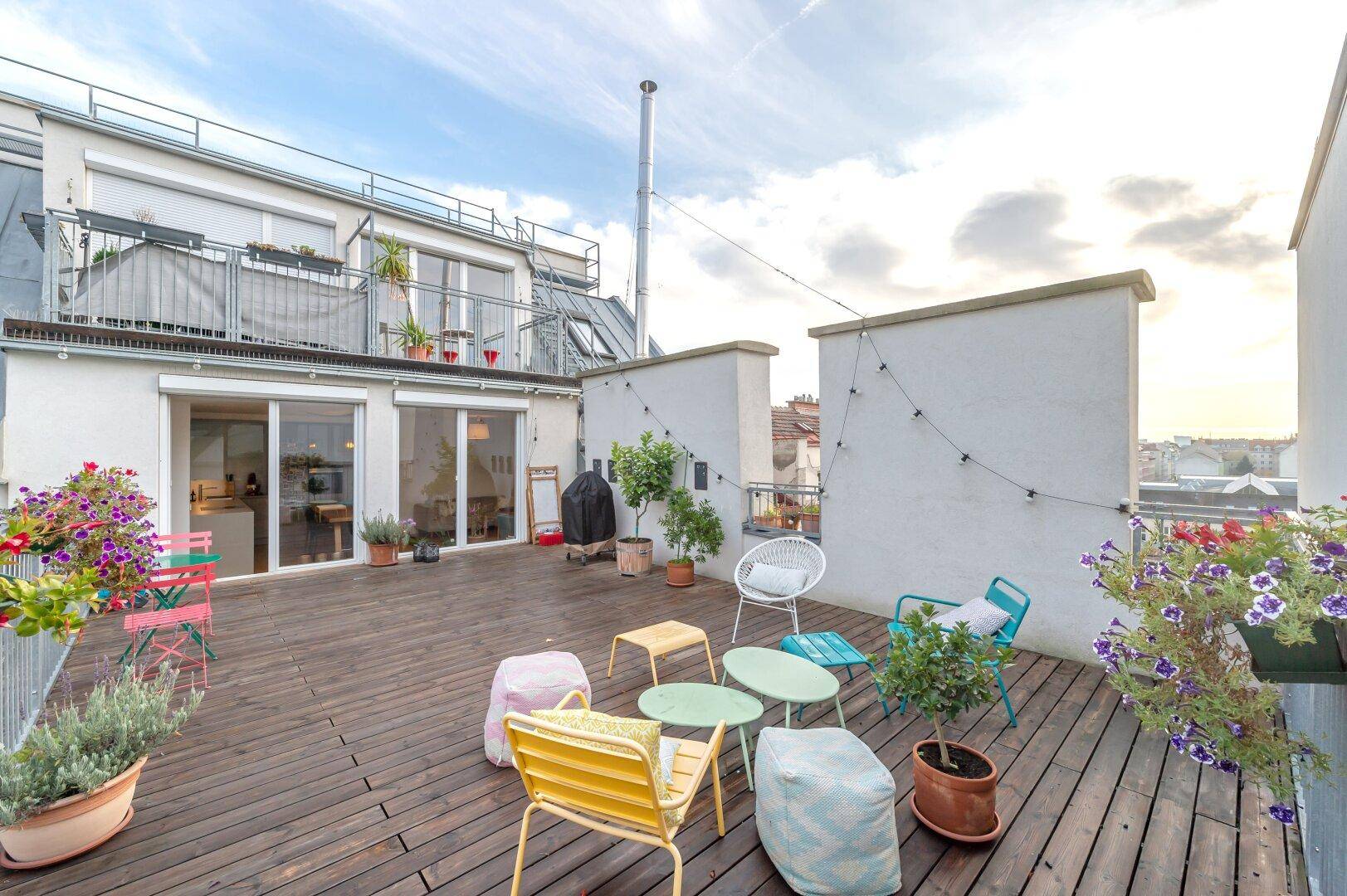 Attraktive Dachterrasse mit Holzboden, gemütlichen Sitzgelegenheiten und Zugang zum Innenbereich.