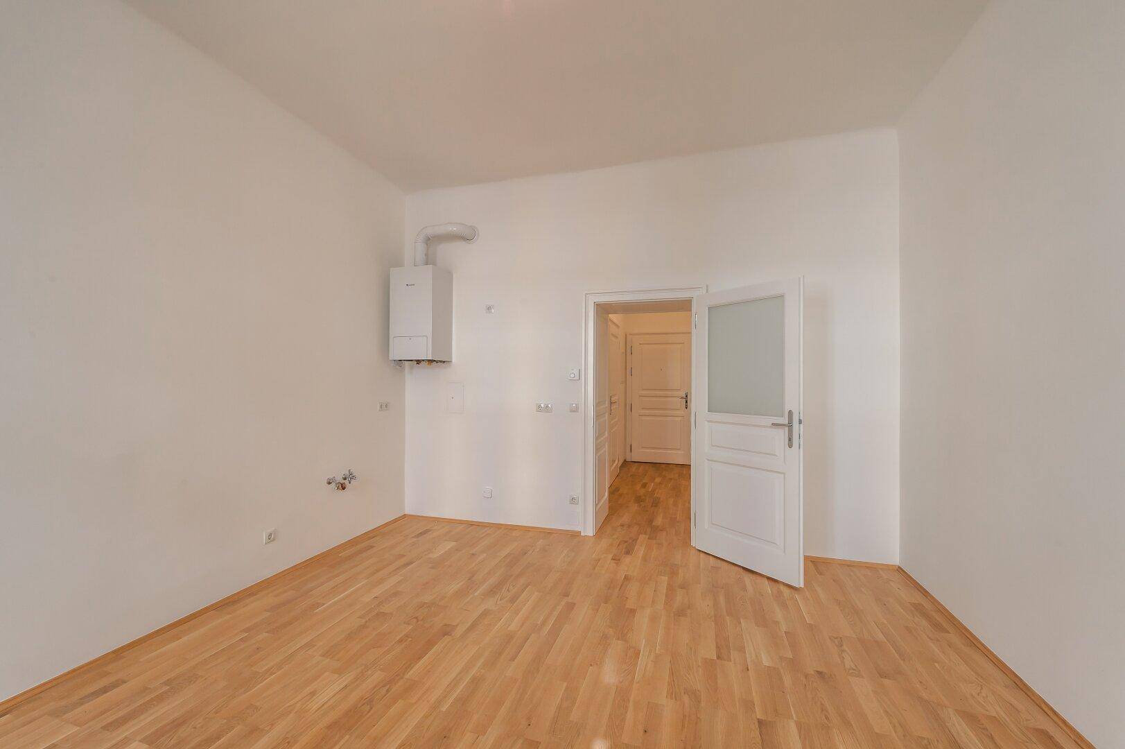 Funktionaler Raum mit Gastherme und Parkettboden, ideal für Waschmaschine oder kleine Küche.