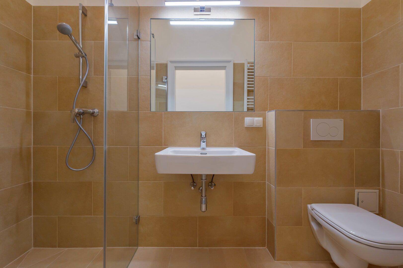 Helles Badezimmer mit Dusche, modernem Waschbecken und beigefarbenen Wand- und Bodenfliesen.