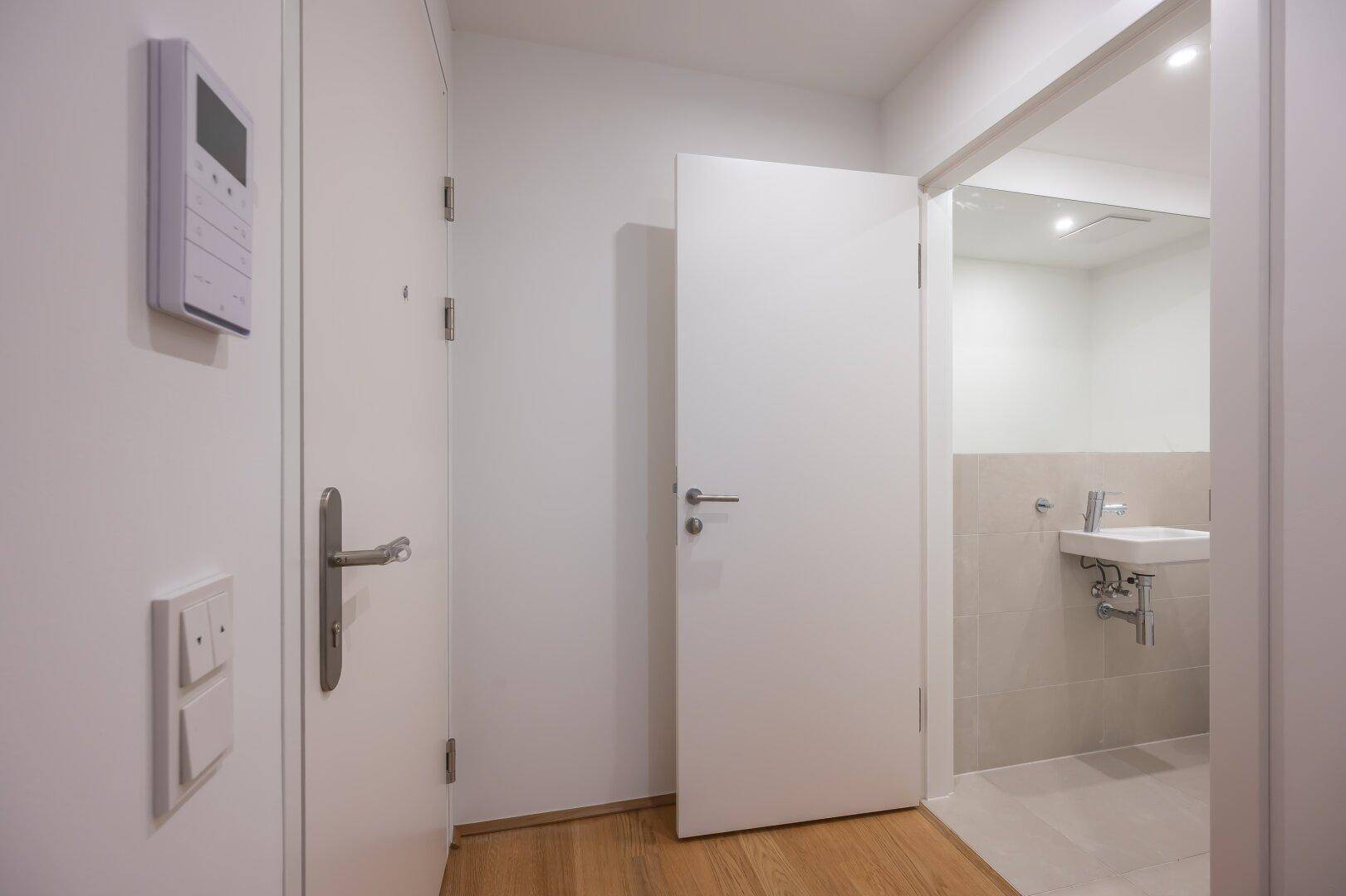 Heller Eingangsbereich mit Holzboden und einer Tür, die zu einem Gäste-WC führt.