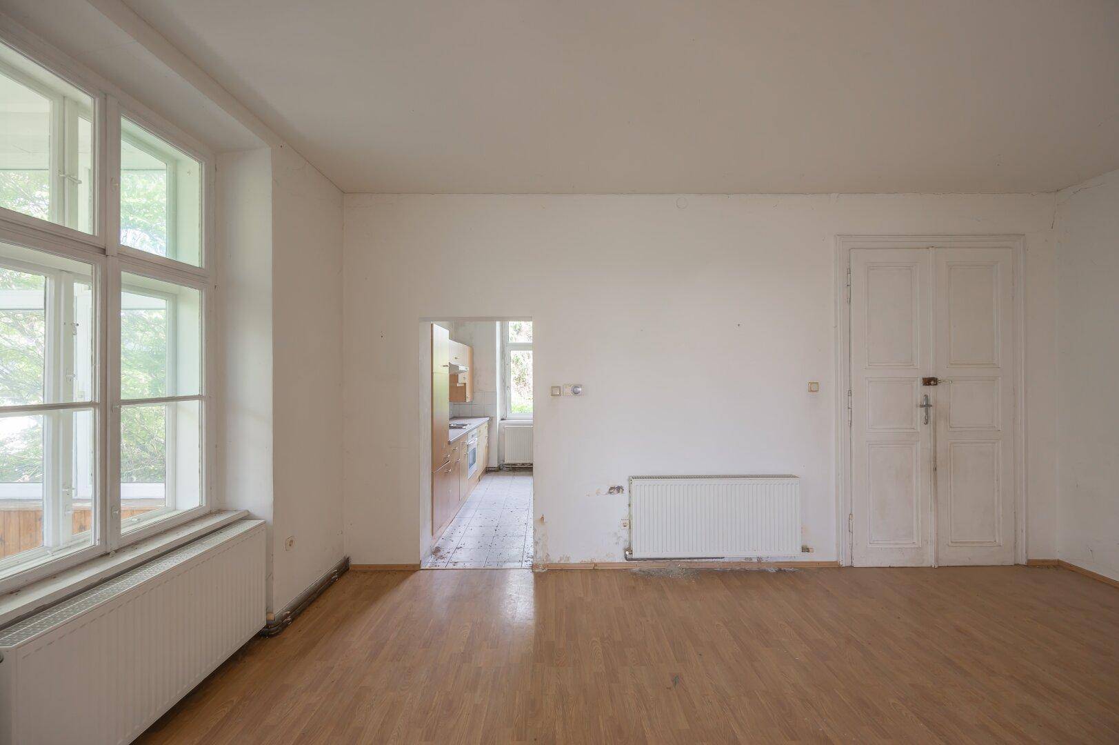 Geräumiges Zimmer mit Laminatboden und Zugang zu einem weiteren Raum, ideal für Renovierung.