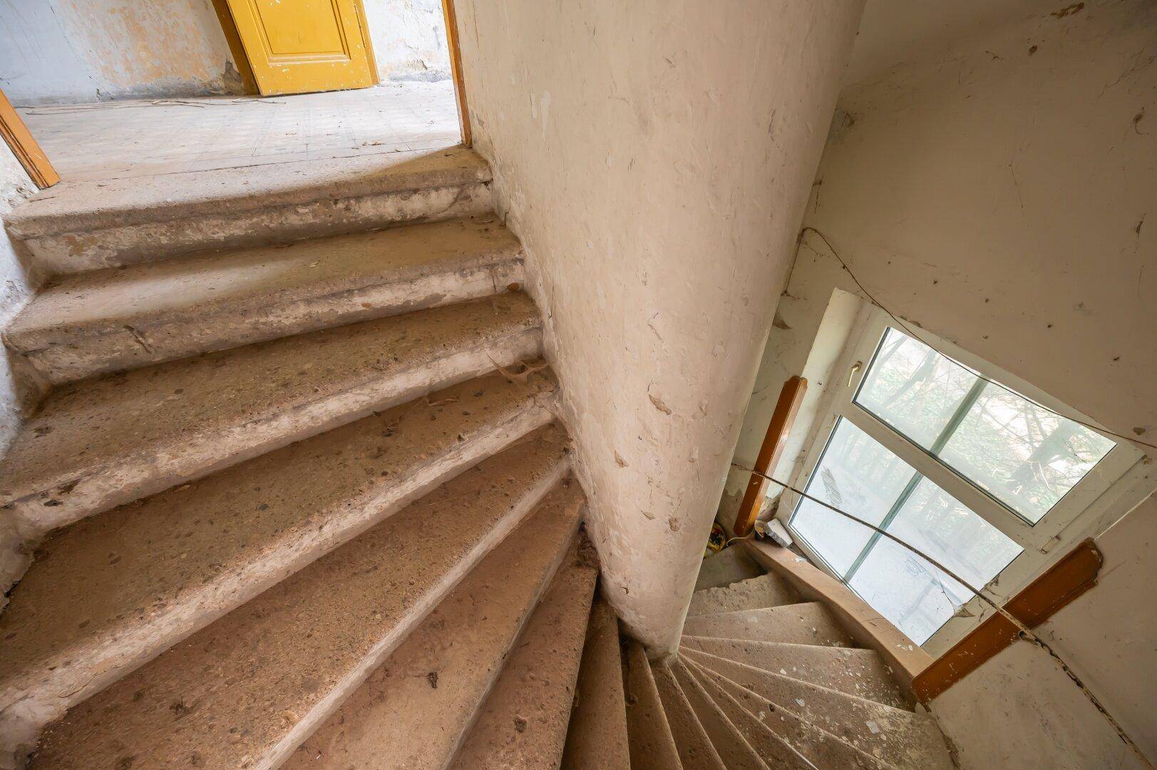 Alte Wendeltreppe aus Stein mit Fenster, die in die oberen Stockwerke führt und saniert werden muss.