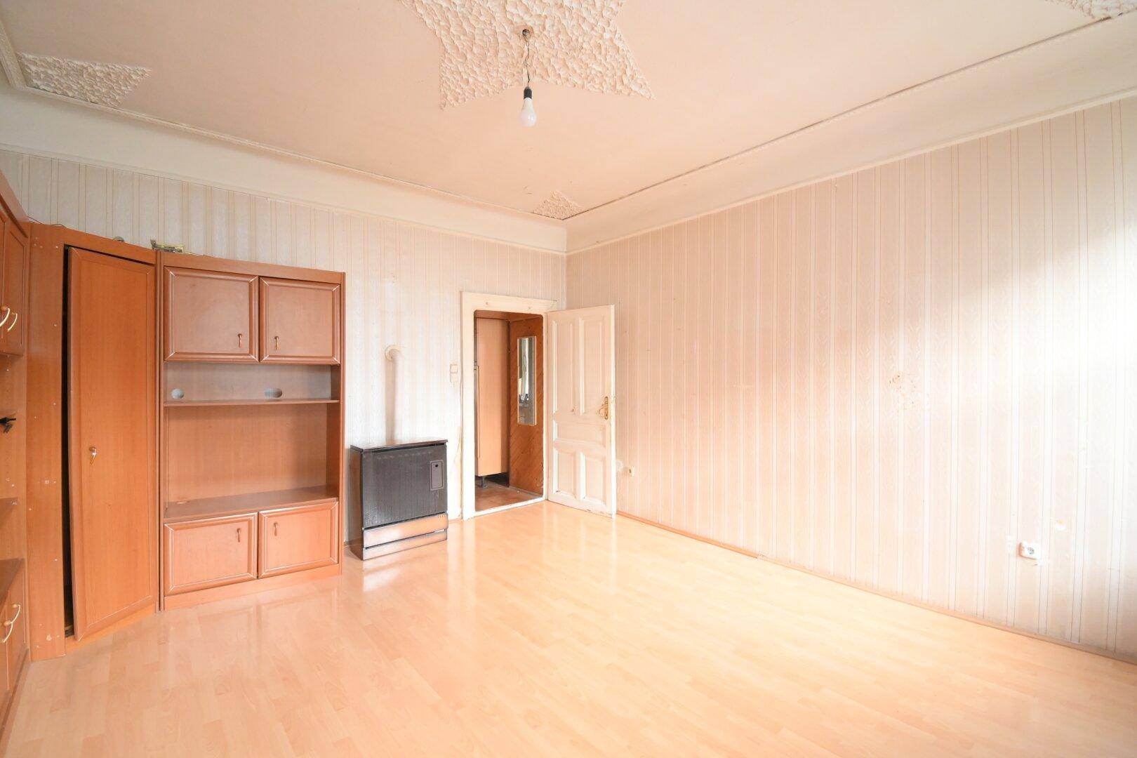 Geräumiges Zimmer mit Laminatboden, Stuckdecke und einem Ofen, der für Wärme sorgt.