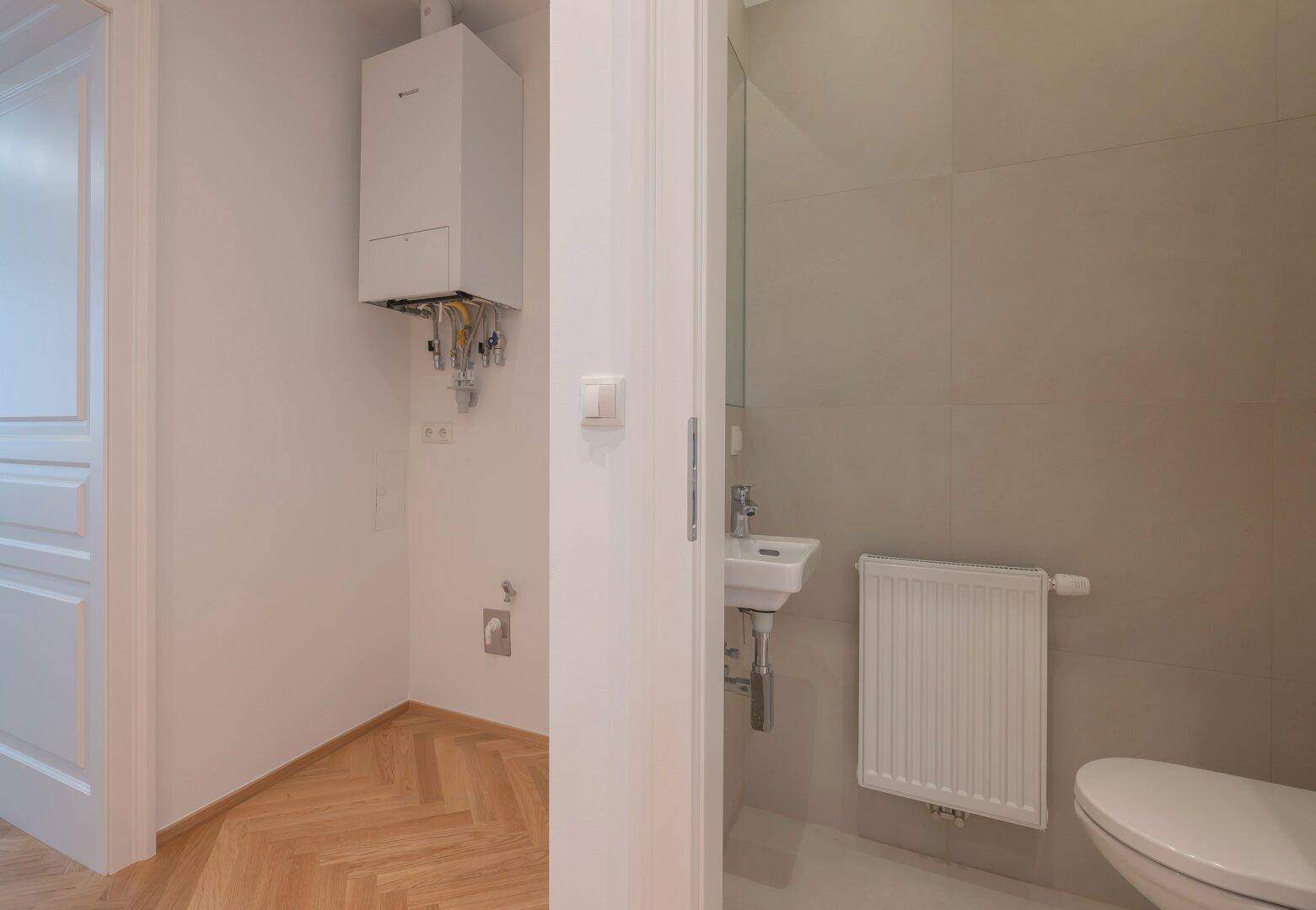 Eingangsbereich mit Heiztherme an der Wand und Blick in das separate Gäste-WC.