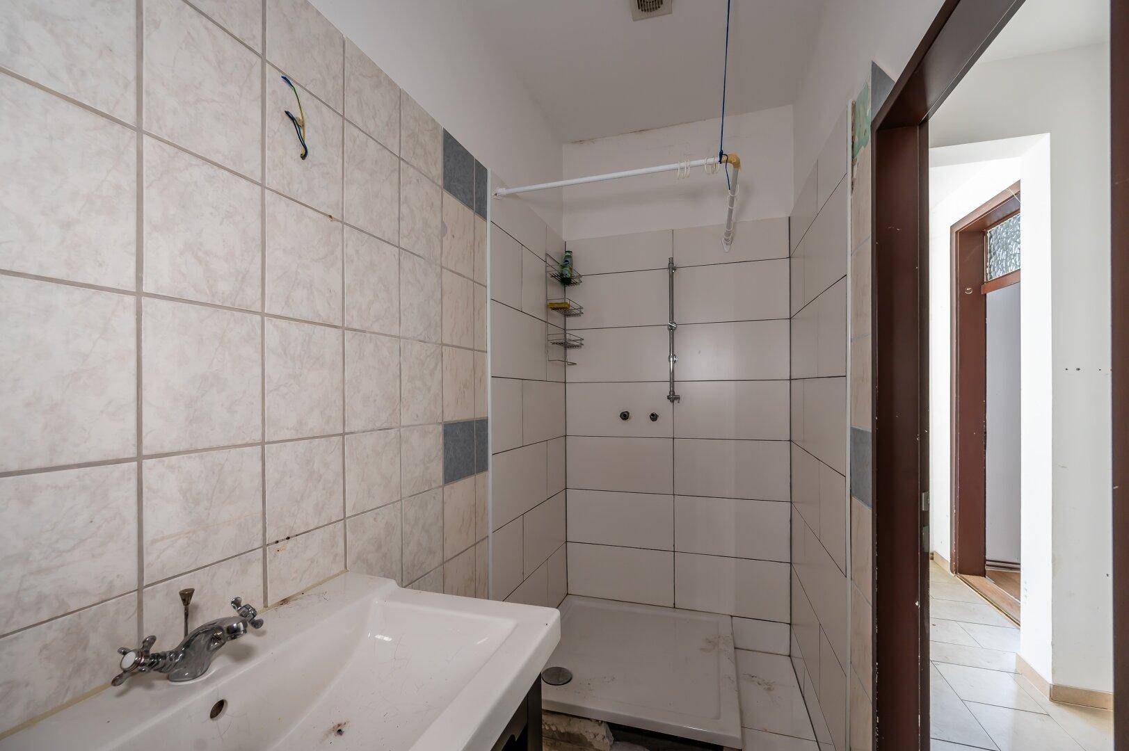 Duschbereich im Badezimmer mit gefliesten Wänden und einfacher Ausstattung.