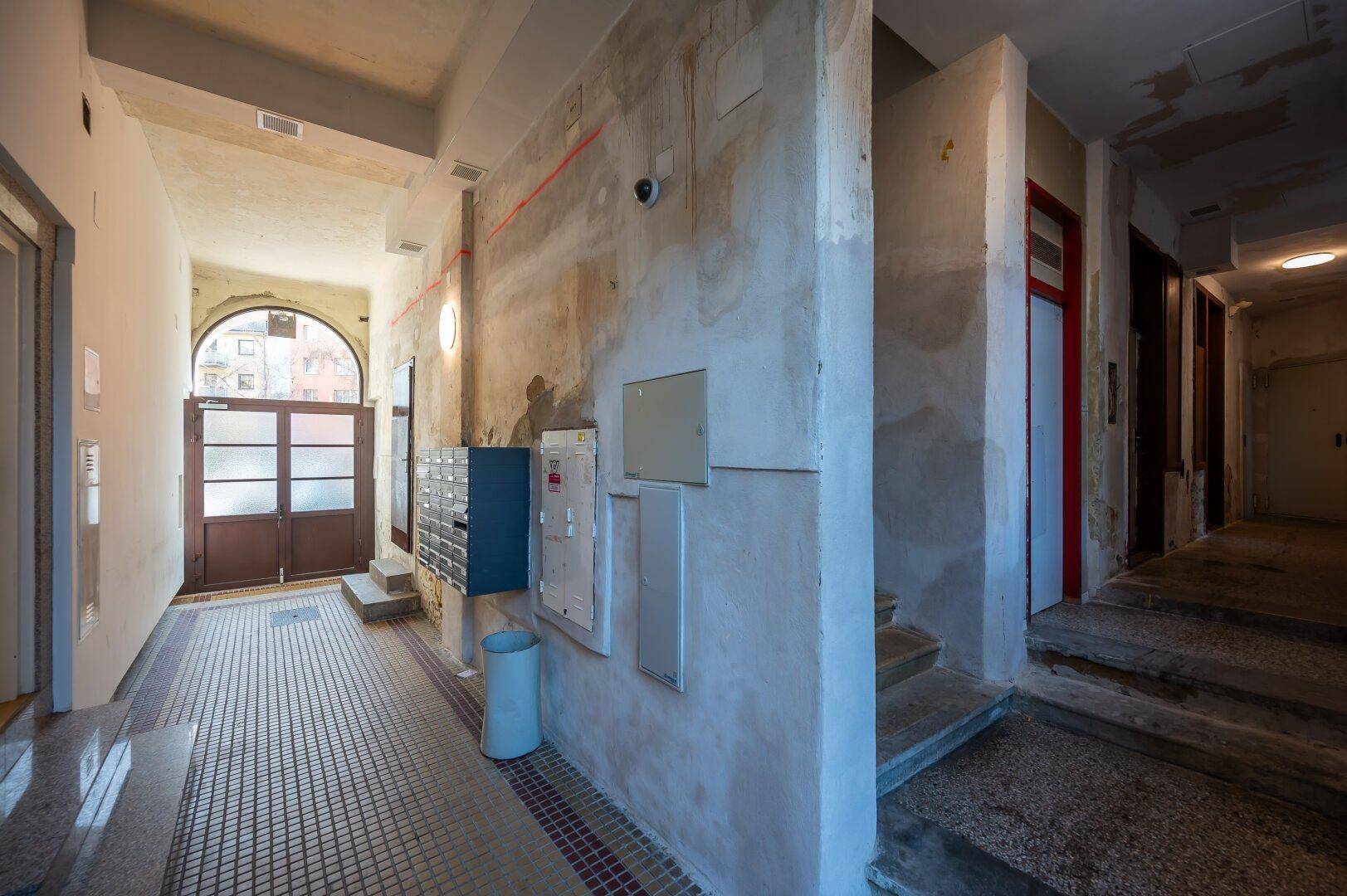 Eingangsbereich des Gebäudes mit Briefkästen, Treppen und Zugang zu den Wohneinheiten.