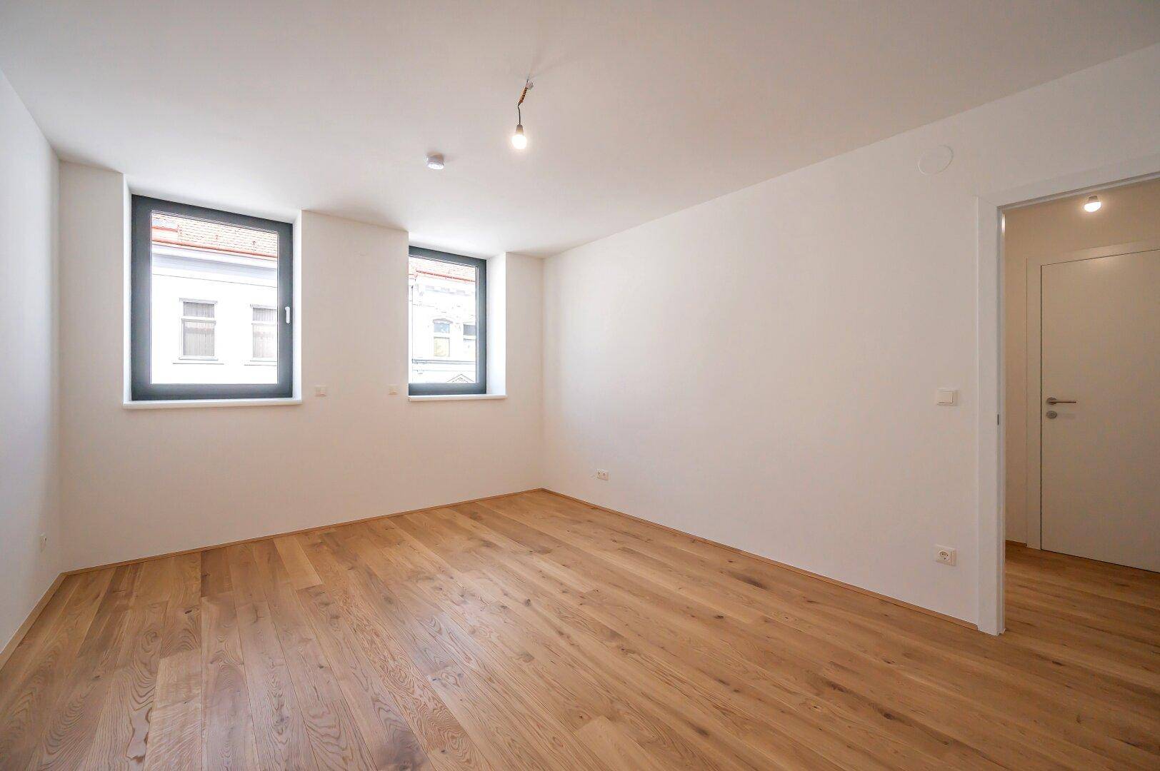 Helles Zimmer mit neuem Eichenparkettboden und zwei Fenstern, ideal als Schlaf- oder Arbeitszimmer.
