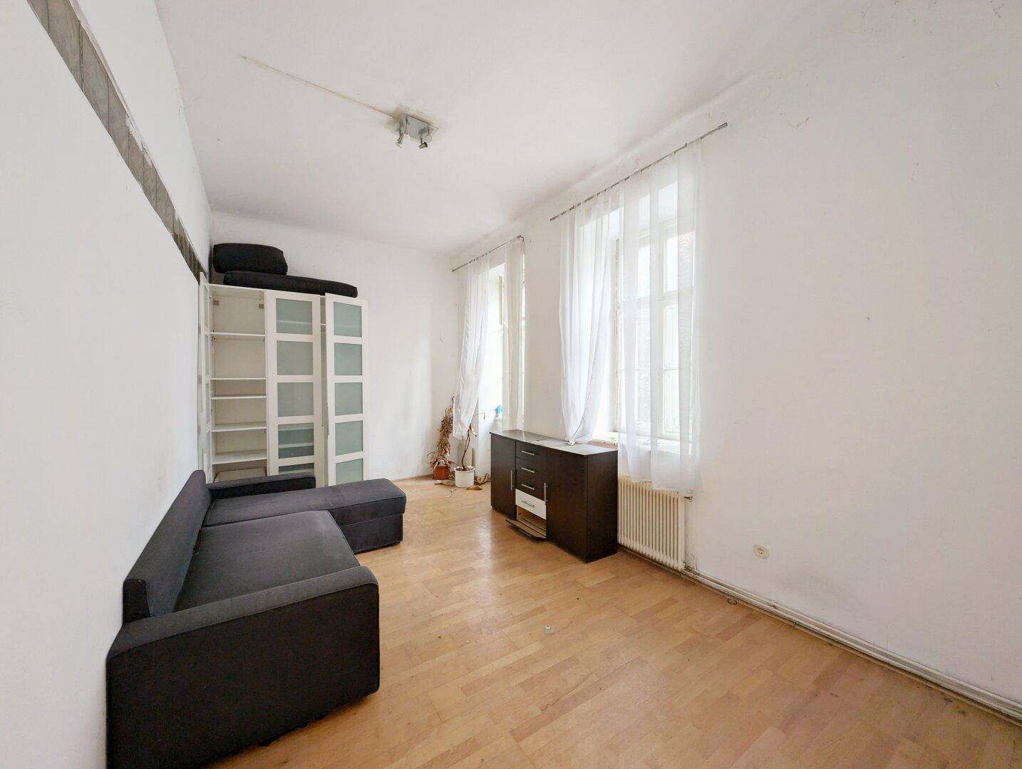 Helles Zimmer mit Parkettboden und einfacher Möblierung, geeignet als Schlaf- oder Arbeitszimmer.