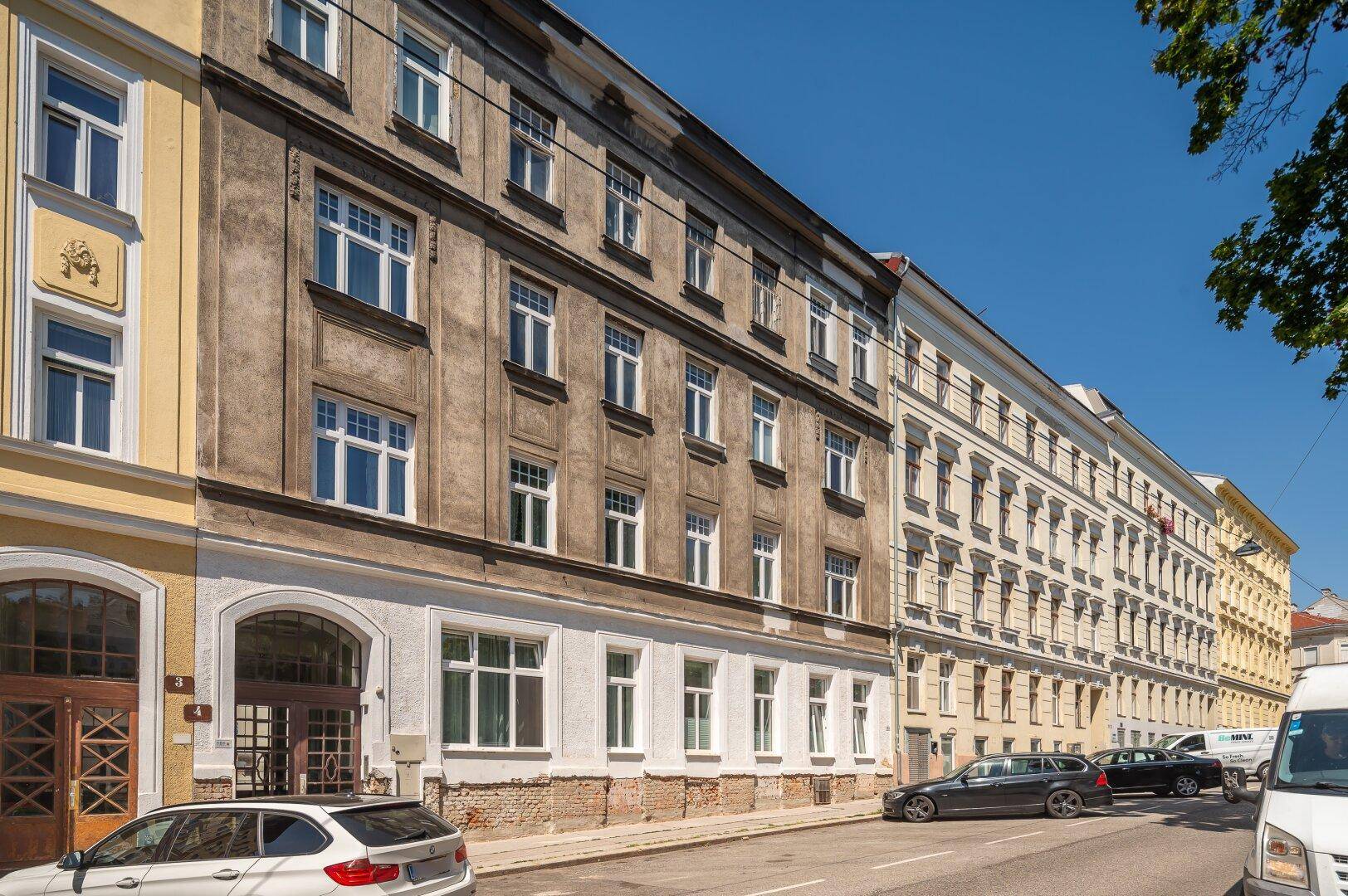 Historische Fassade eines Mehrfamilienhauses an einer belebten Stadtstraße.