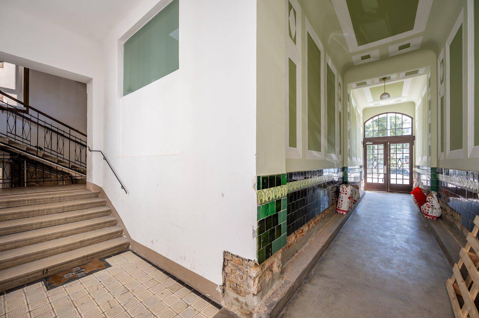 Historisches Treppenhaus mit Fliesenboden und dekorativen Elementen im Eingangsbereich eines Altbaus.