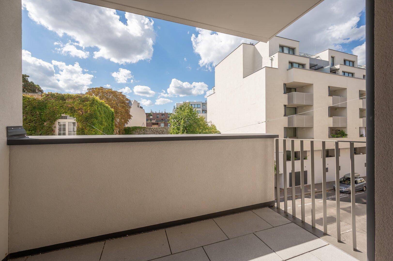 Balkon mit Blick auf moderne Gebäude und begrünte Fassaden in der Umgebung.